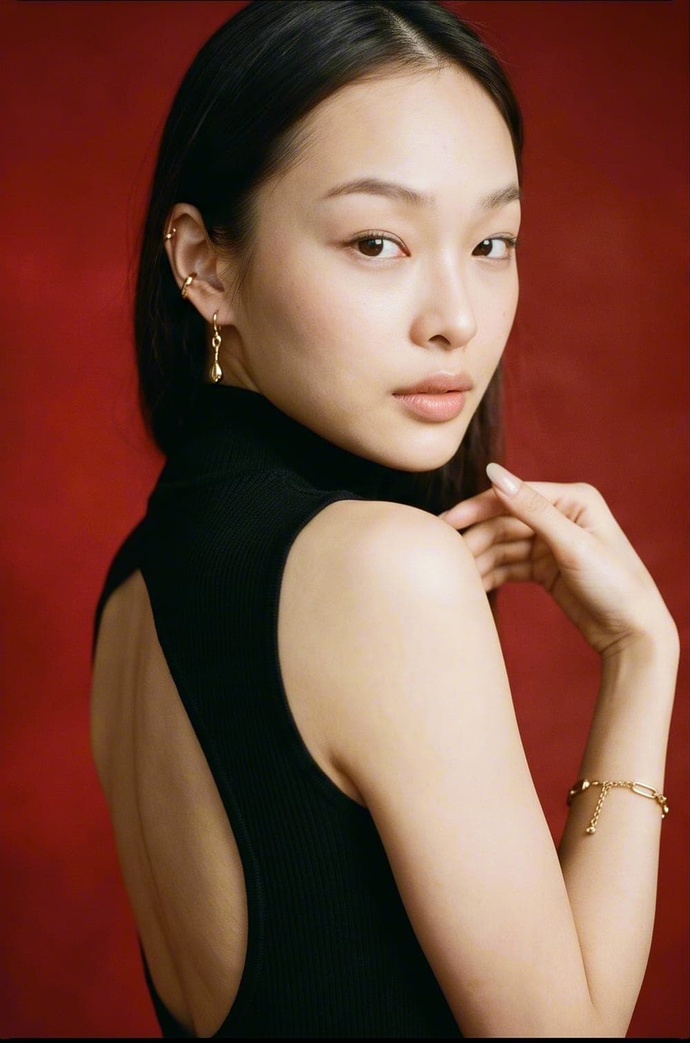 Model in a black look against a deep-red backdrop